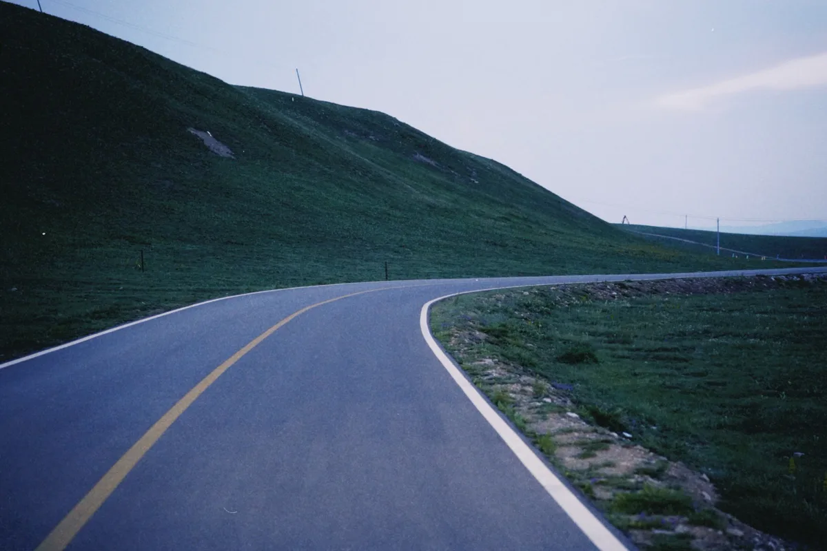 公路沿绿色草坡弯向远处