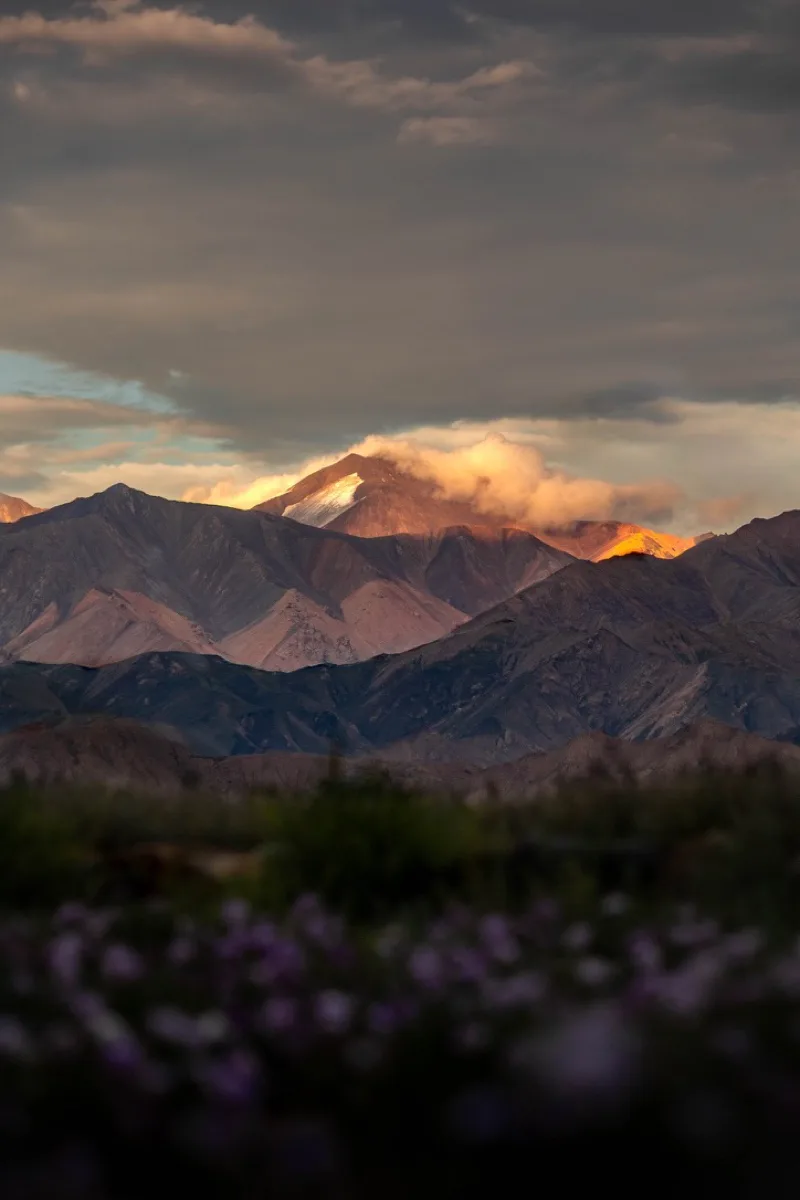 云层间的夕光照亮远处雪山