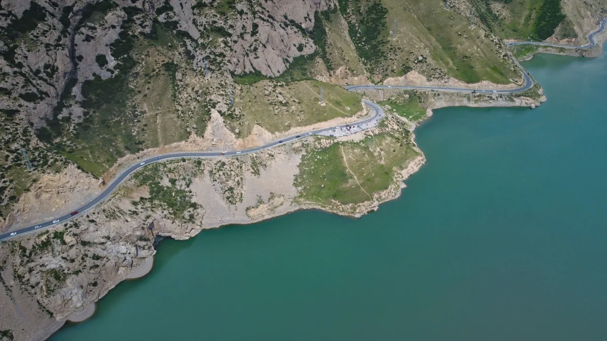 蓝绿色湖岸与蜿蜒公路从群山间穿过