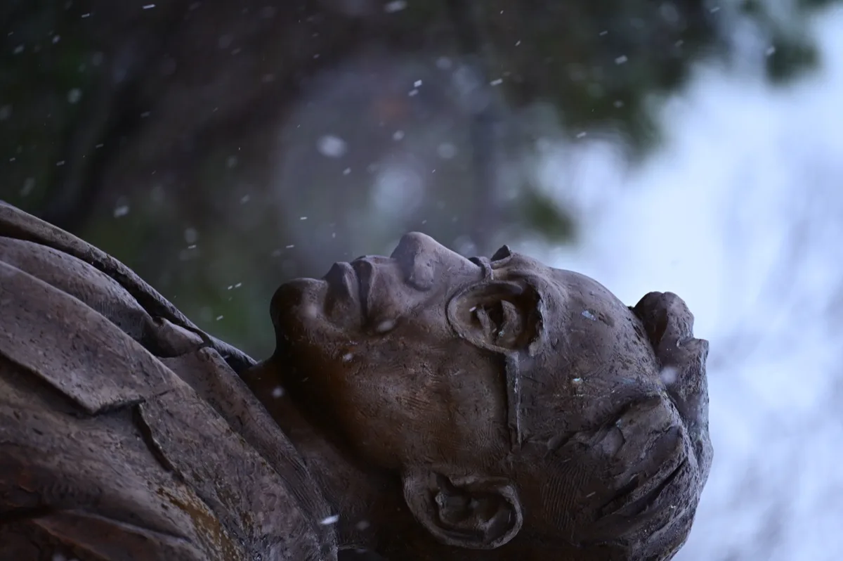雨珠掠过深色石像的侧脸