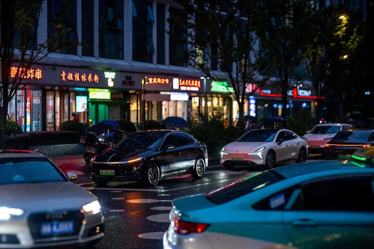 雨夜街道上车灯与店铺霓虹映在湿润路面