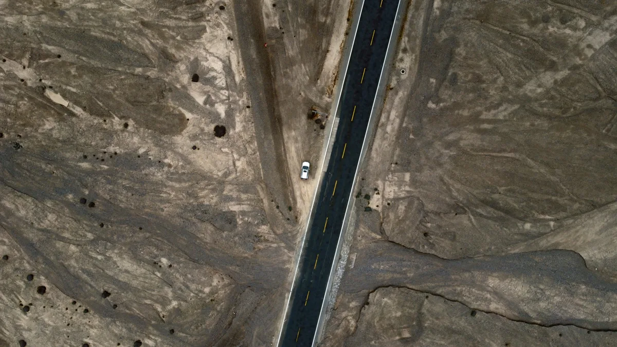 笔直公路穿过褐色荒原，一辆车行驶其上