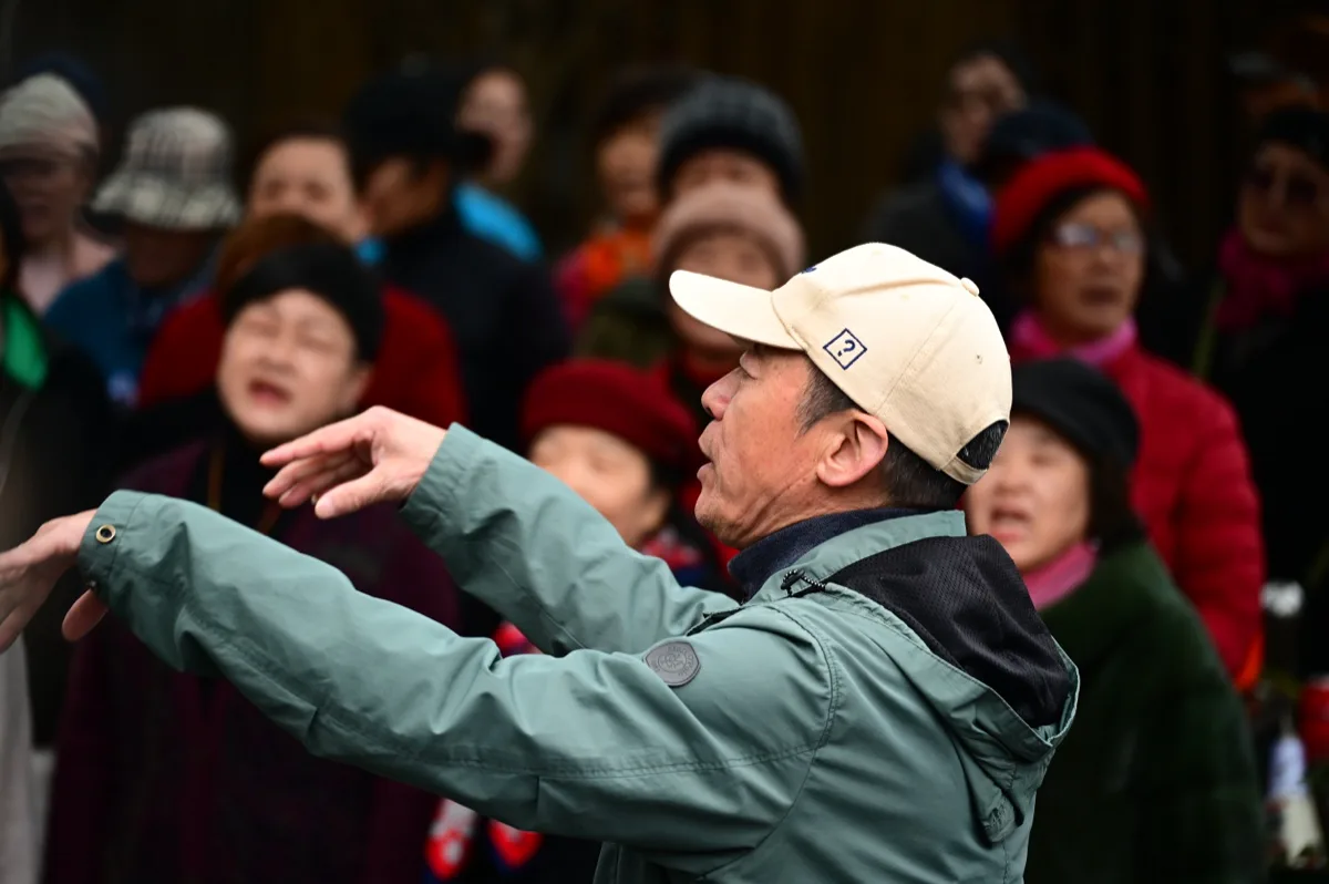 戴帽男子在人群前张开双臂高声歌唱