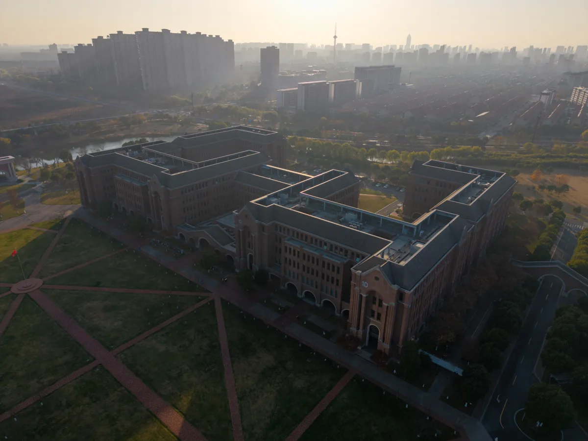 薄雾与低角度阳光笼罩校园建筑和远处城区