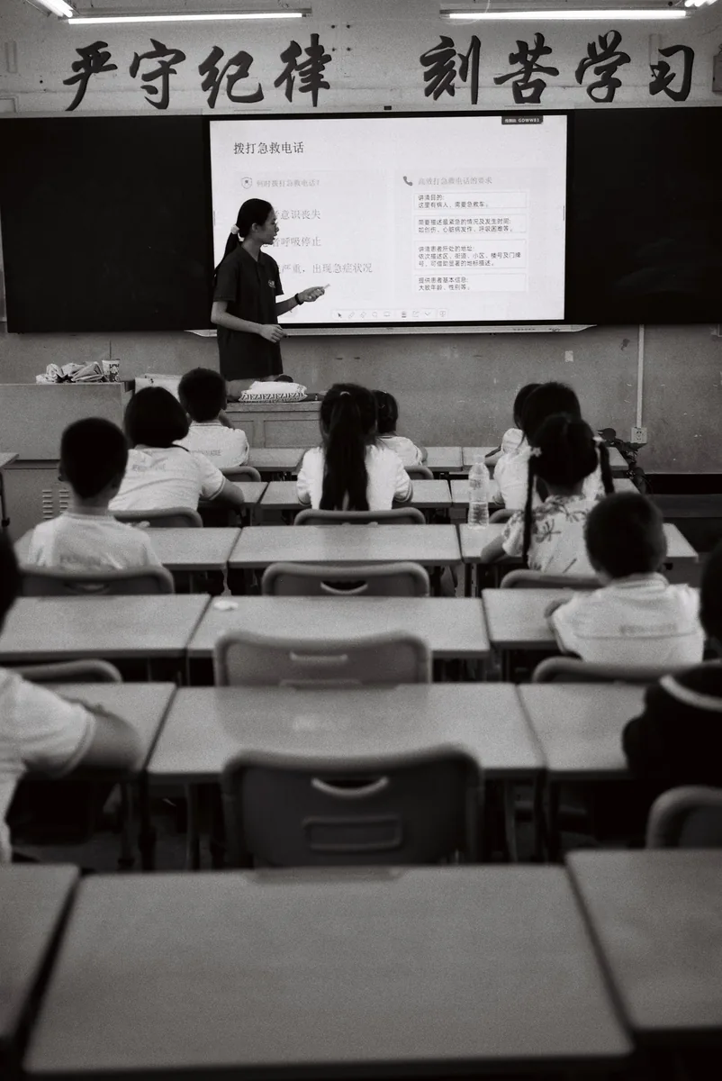 学生坐在课桌前观看投影与讲台上的老师