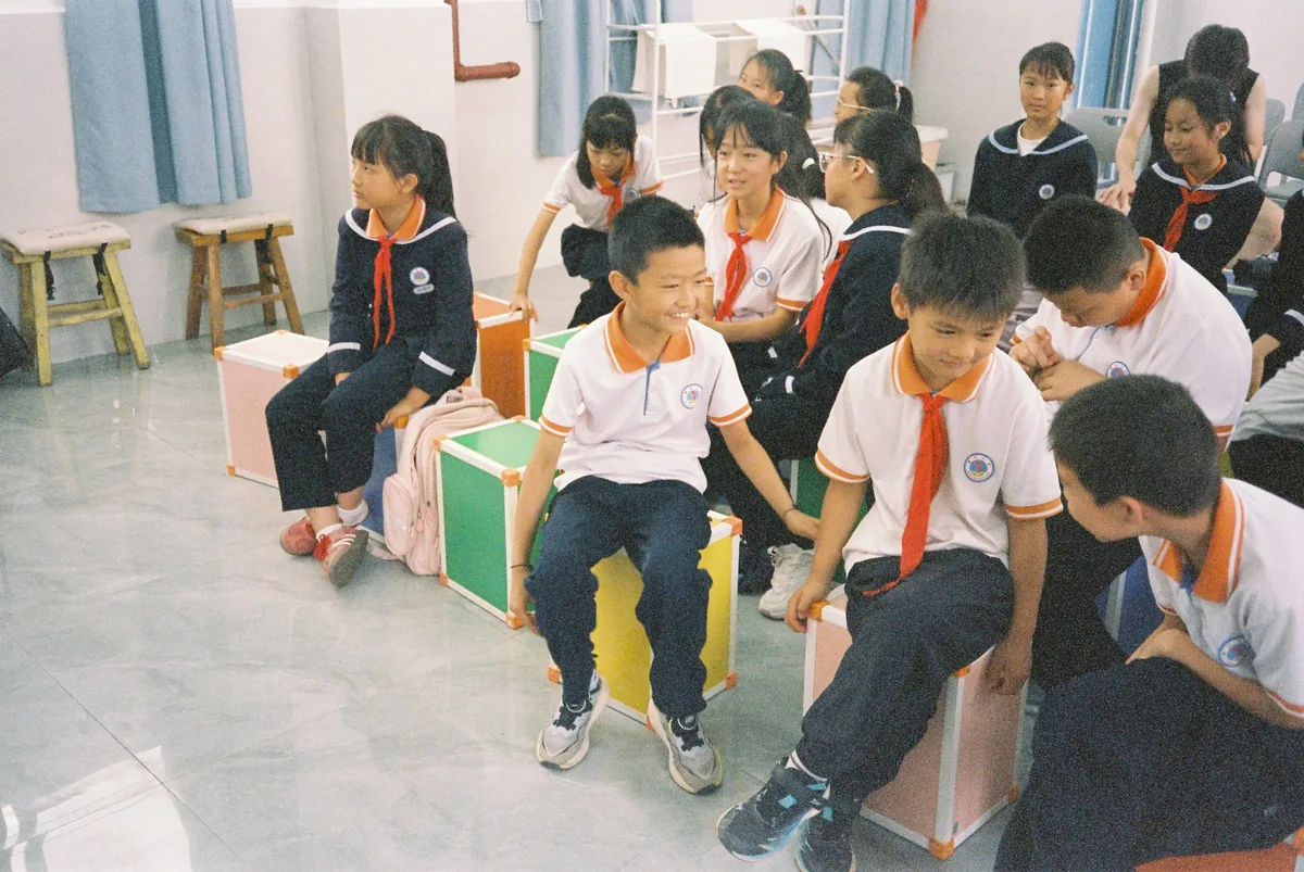 孩子们坐在彩色小椅子上笑着交谈
