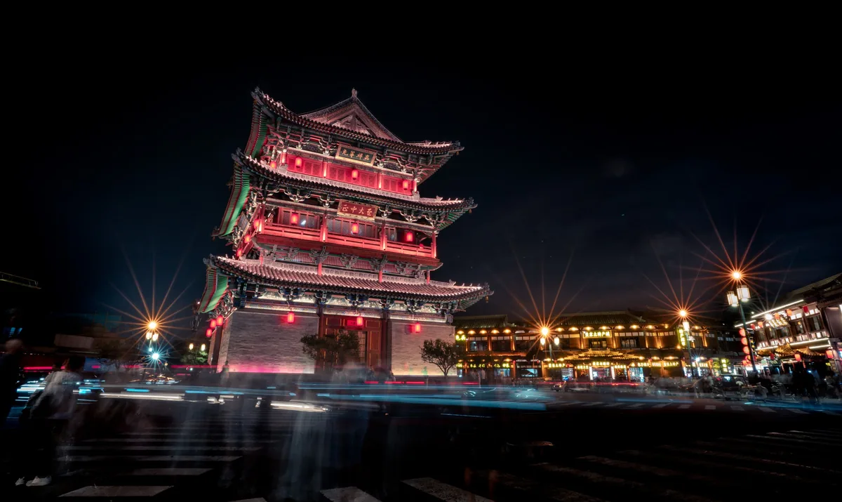 夜间亮灯的红色鼓楼前车流形成光轨