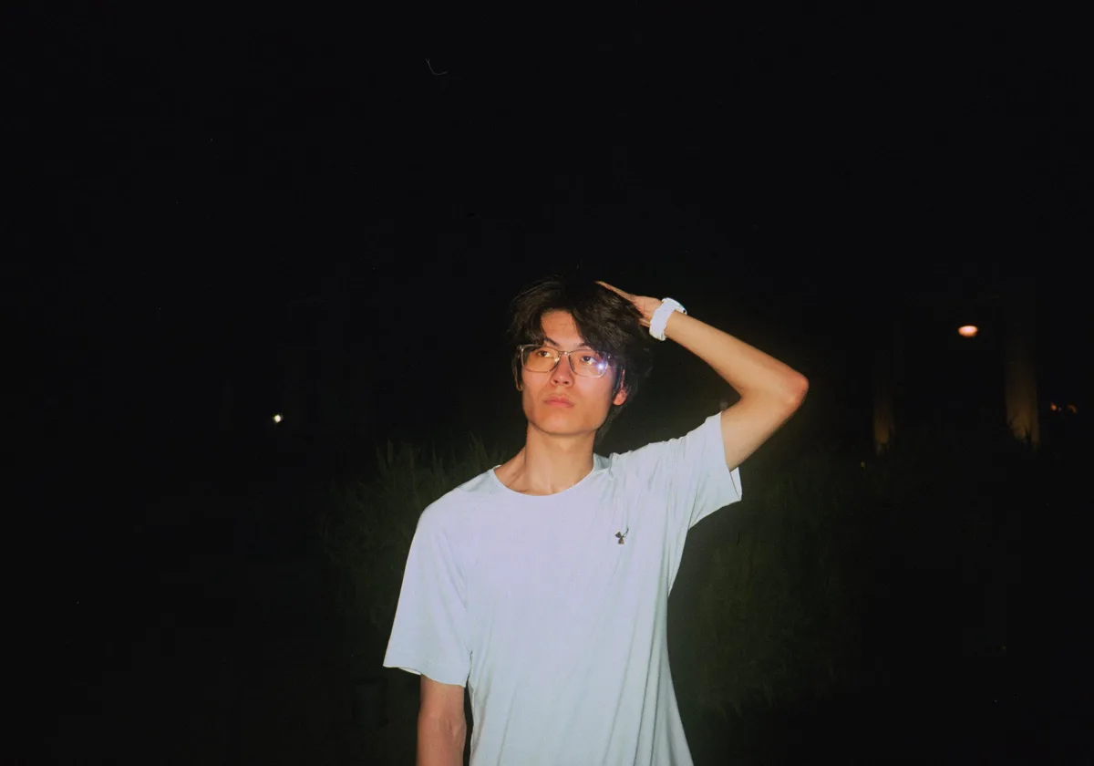 夜色中一名戴眼镜的青年站在闪光灯前